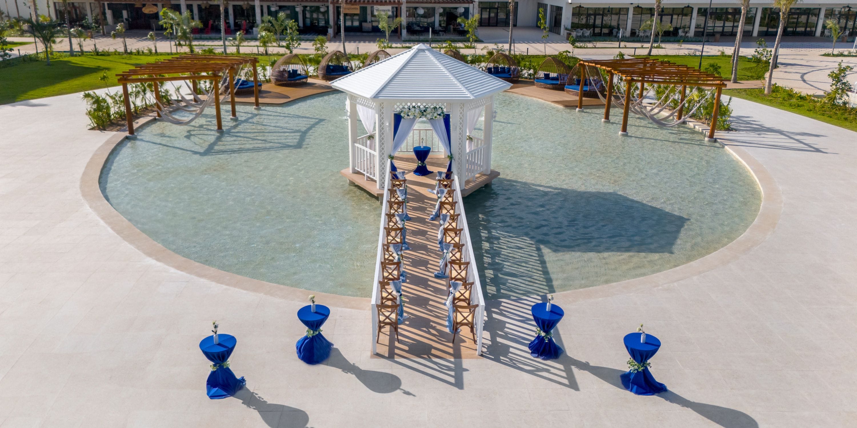 Ocean Allure Costa Mujeres offers a stunning wedding gazebo in a shallow pool with bridges and blue tables.