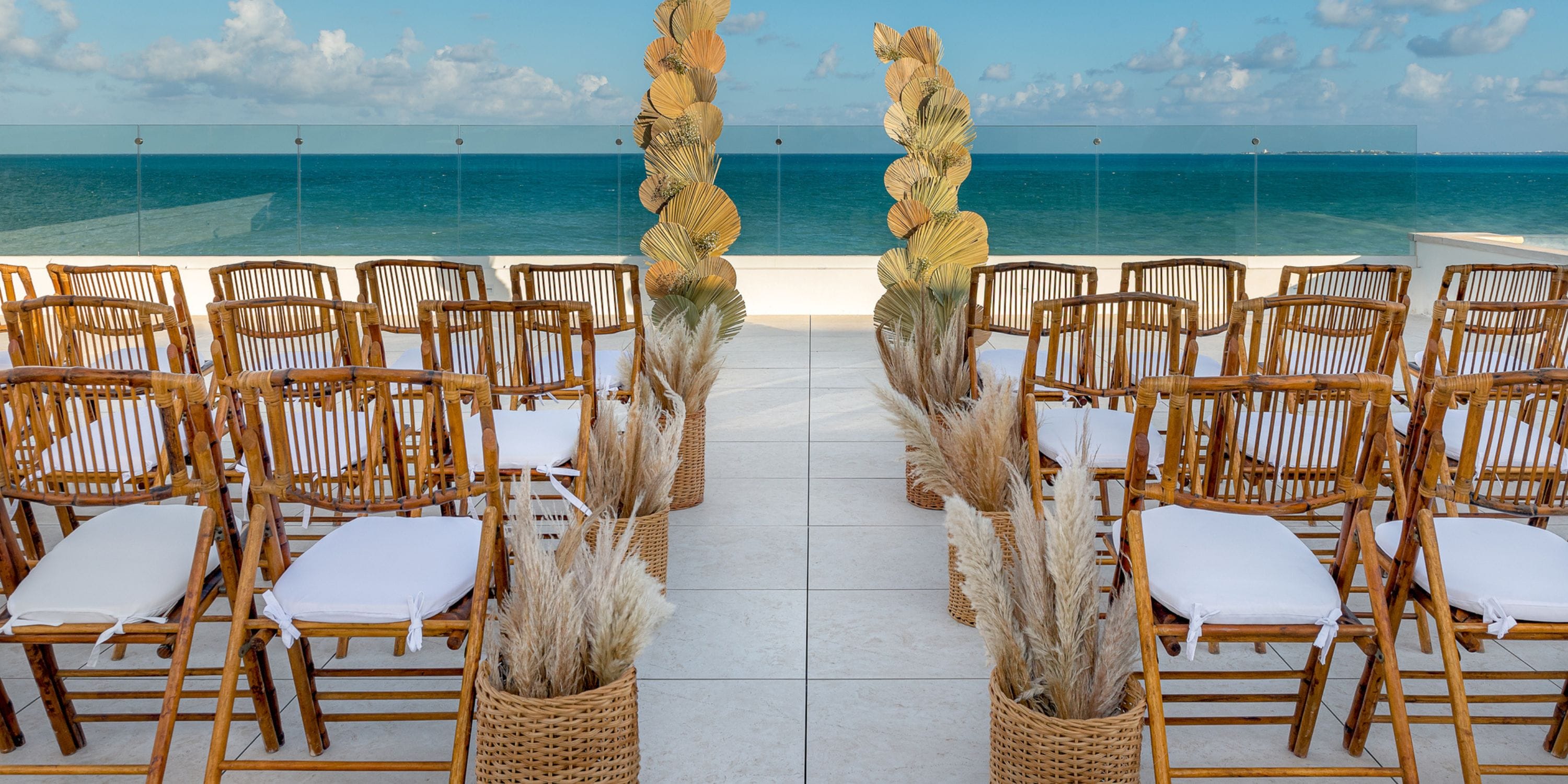 Ocean Allure Costa Mujeres showcases rows of wooden chairs and dried plants set for a destination wedding.