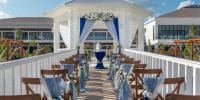 Ocean Allure Costa Mujeres: Destination wedding setup with wooden chairs, blue accents, and floral arch.
