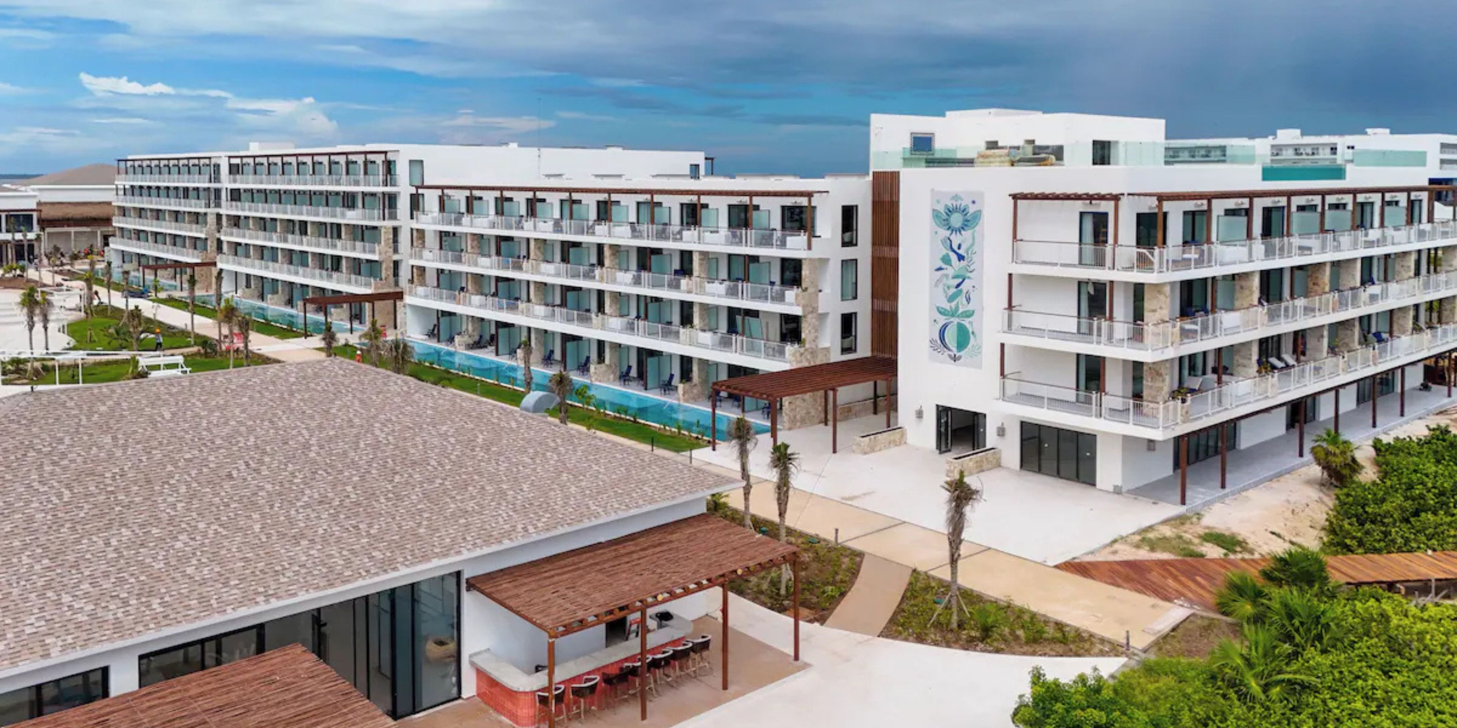 Ocean Coral and Turquesa: modern beachfront hotel, ideal for destination weddings, with balconies, pools, and palm trees.