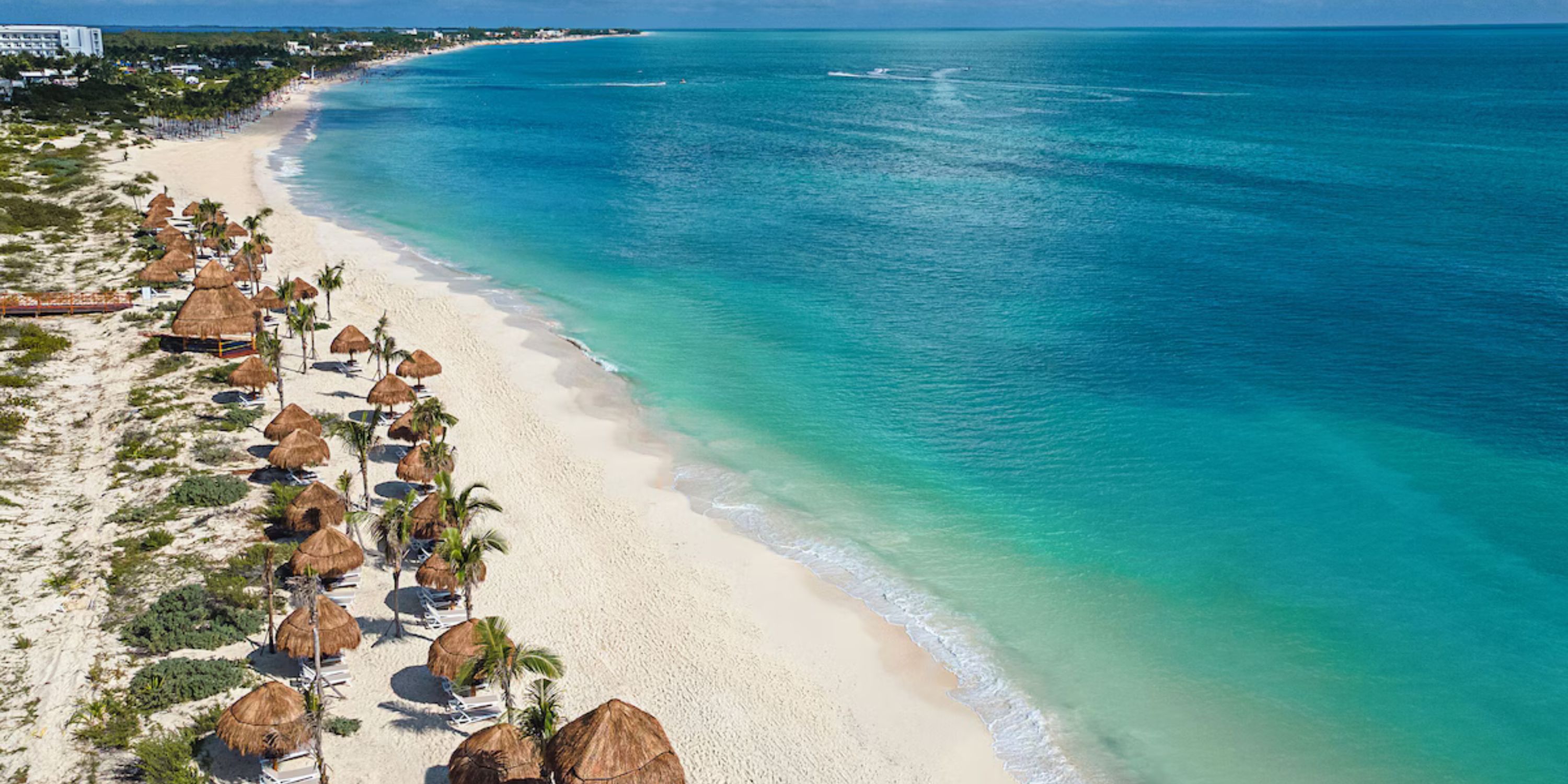 Aerial view of Ocean Coral and Turquesa, perfect for a destination wedding: beach, palapas, blue sky.