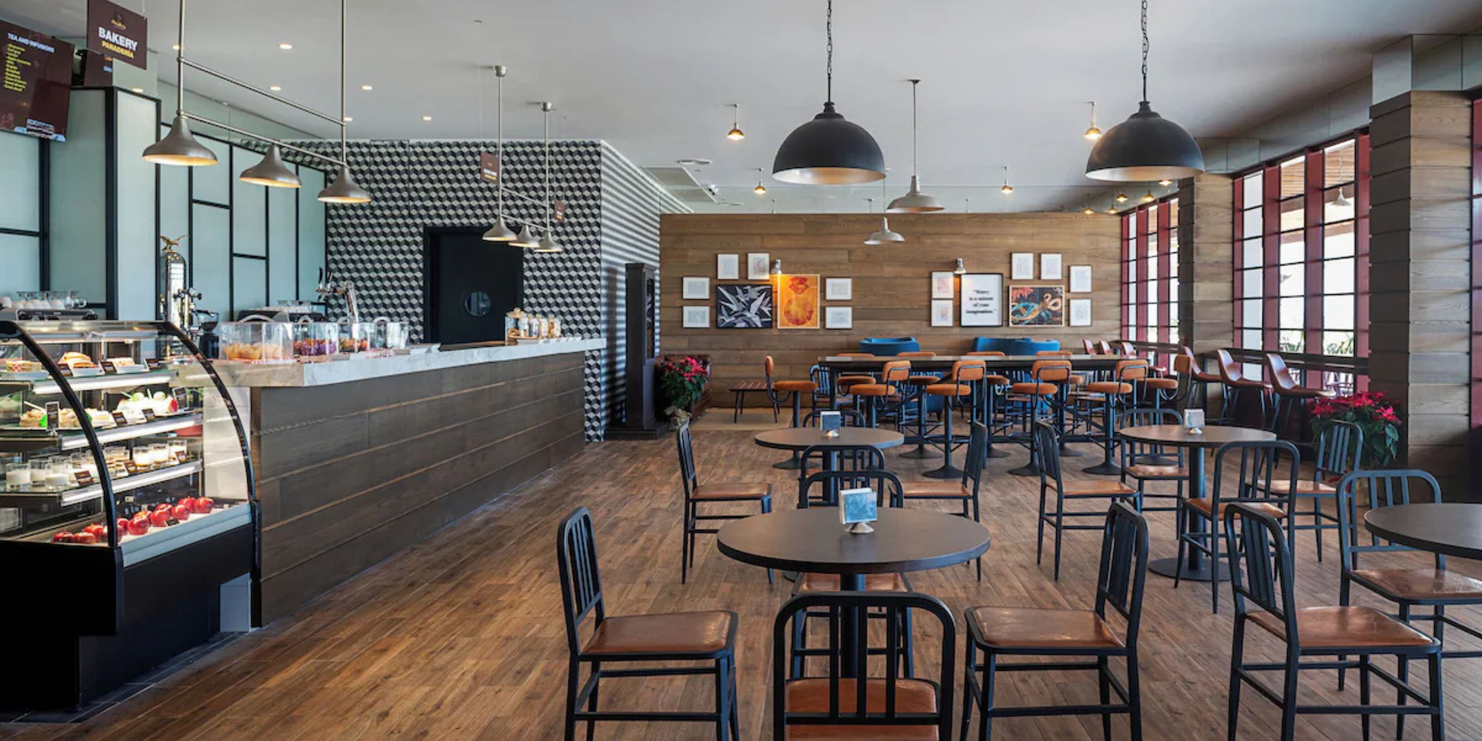 Modern caf&eacute; with wooden tables, chairs, counter, and wall art&mdash;ideal for a destination wedding event.