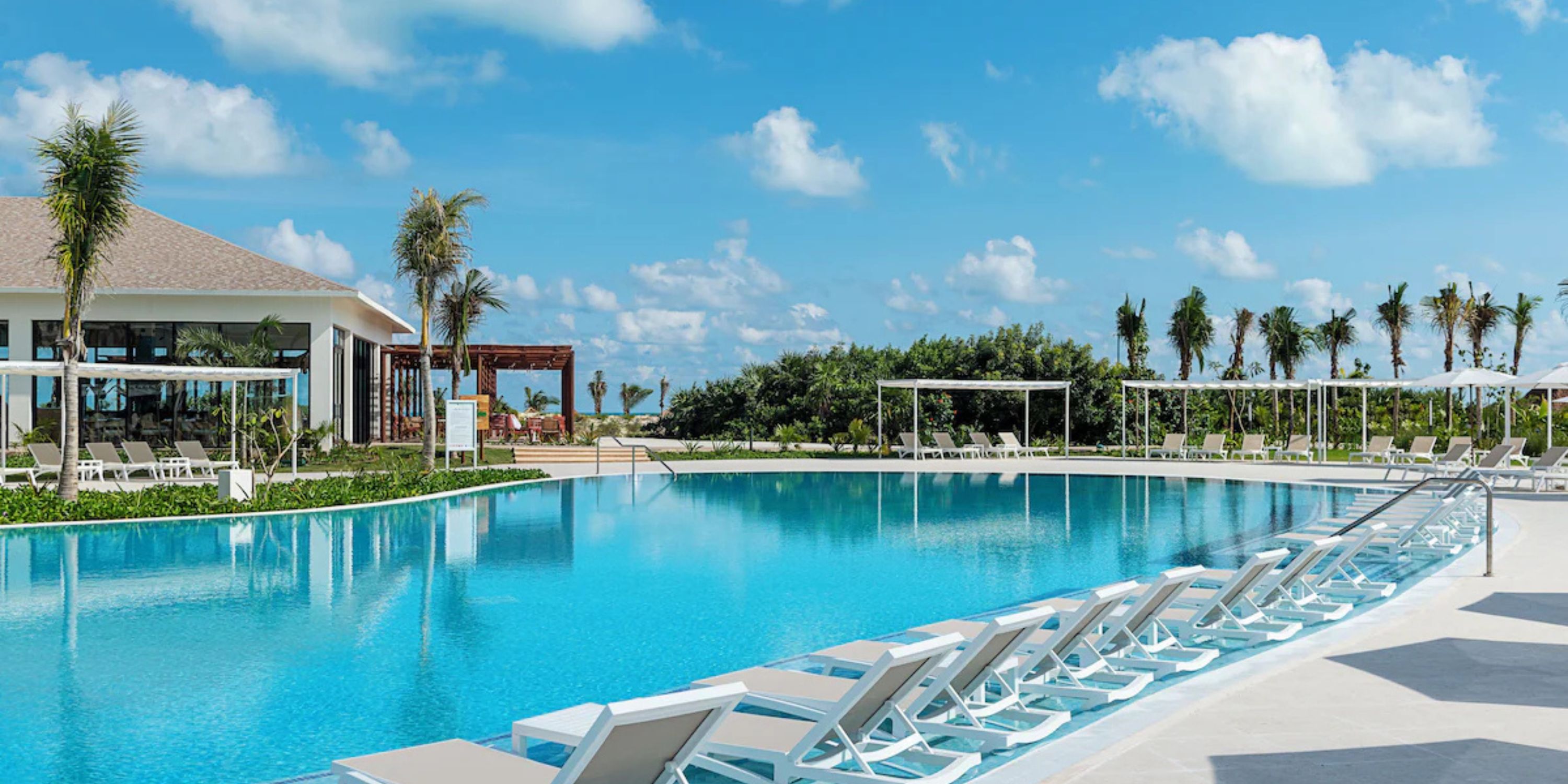 Ocean Coral and Turquesa's large pool with lounge chairs and palm trees is ideal for a destination wedding.