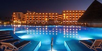Ocean Coral and Turquesa hotel and pool lit up at night, perfect for a destination wedding by the water.