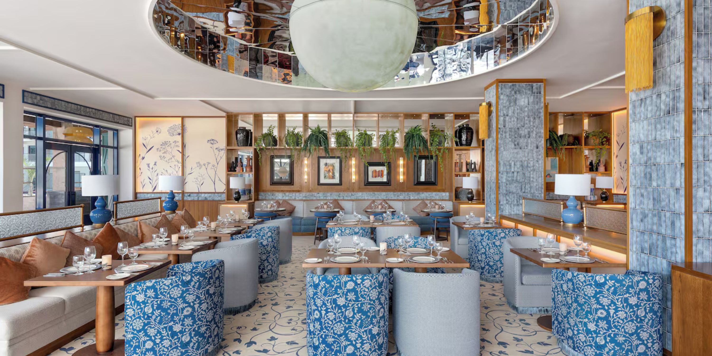 Chic restaurant at Ocean Coral and Turquesa, perfect for a destination wedding, with blue chairs, wood tables, and lush plants.