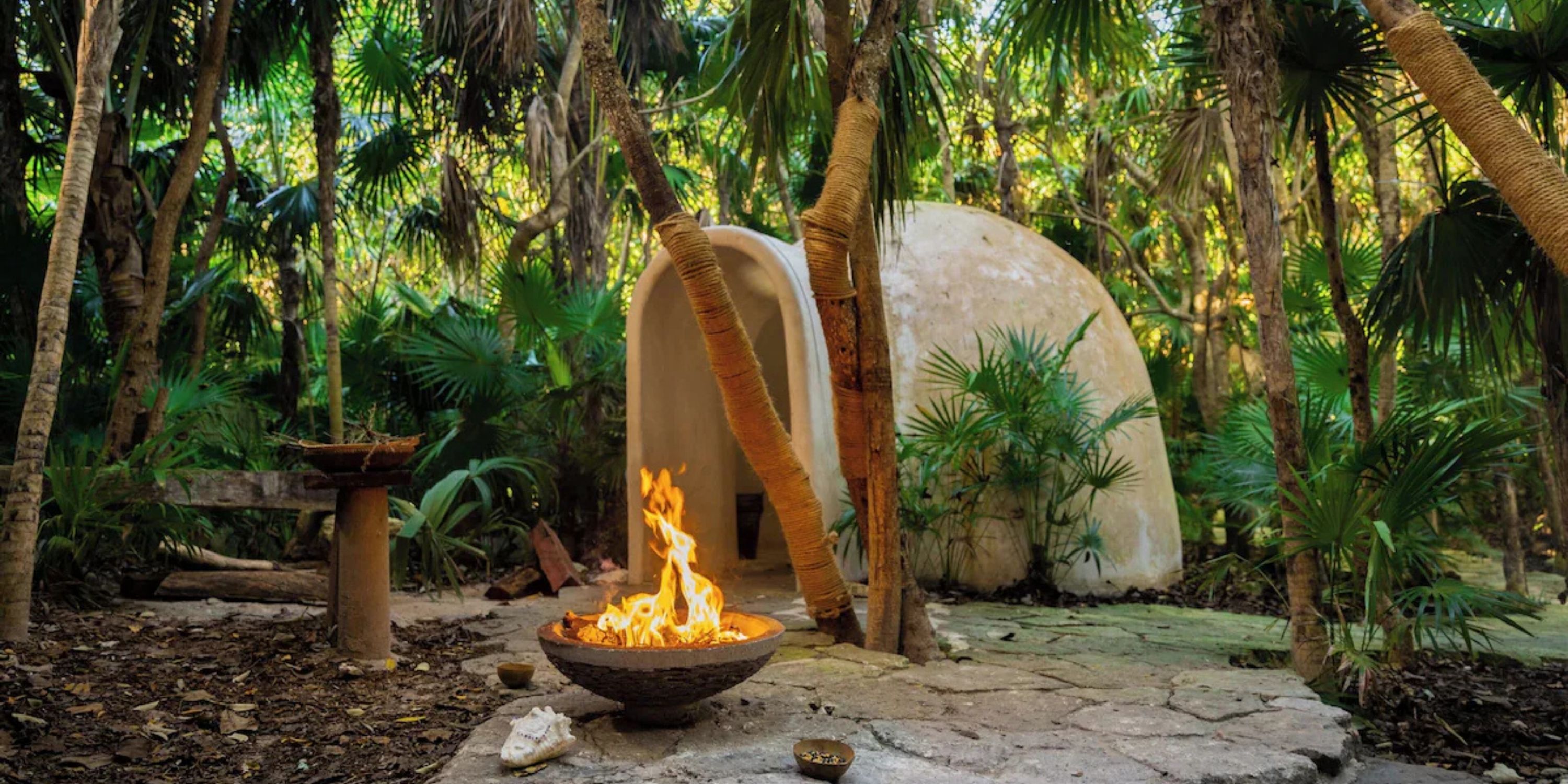 A fire in a bowl at Sandos Playacar during a destination wedding ceremony in a forest setting.
