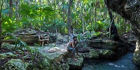 A man sits by a pool at Sandos Playacar, a popular destination wedding spot with jungle and rustic decor.