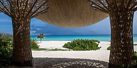 Ocean and sandy beach view at Sandos Playacar, framed by a thatched wedding structure&mdash;perfect destination wedding.
