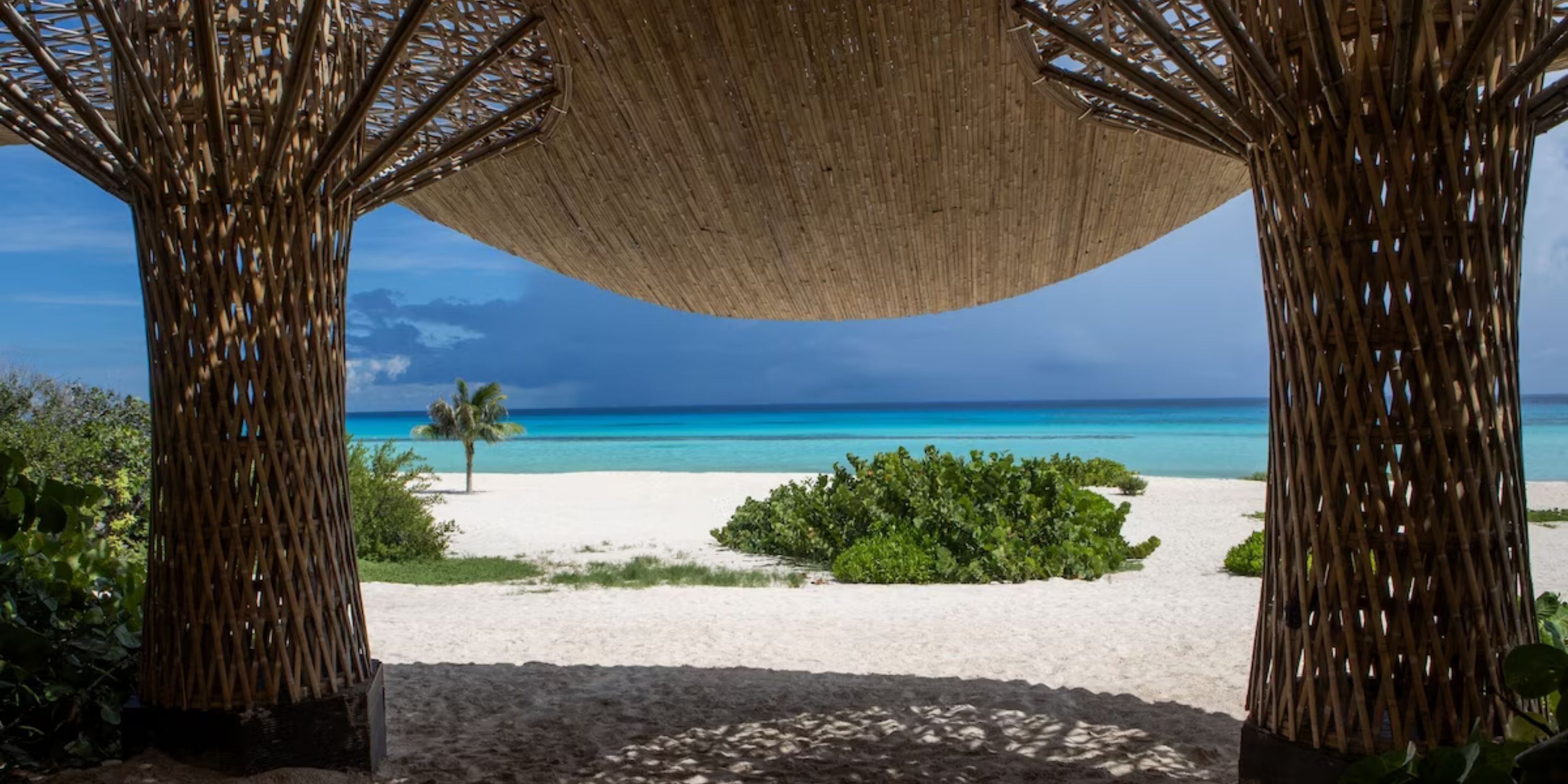 Ocean and sandy beach view at Sandos Playacar, framed by a thatched wedding structure—perfect destination wedding.