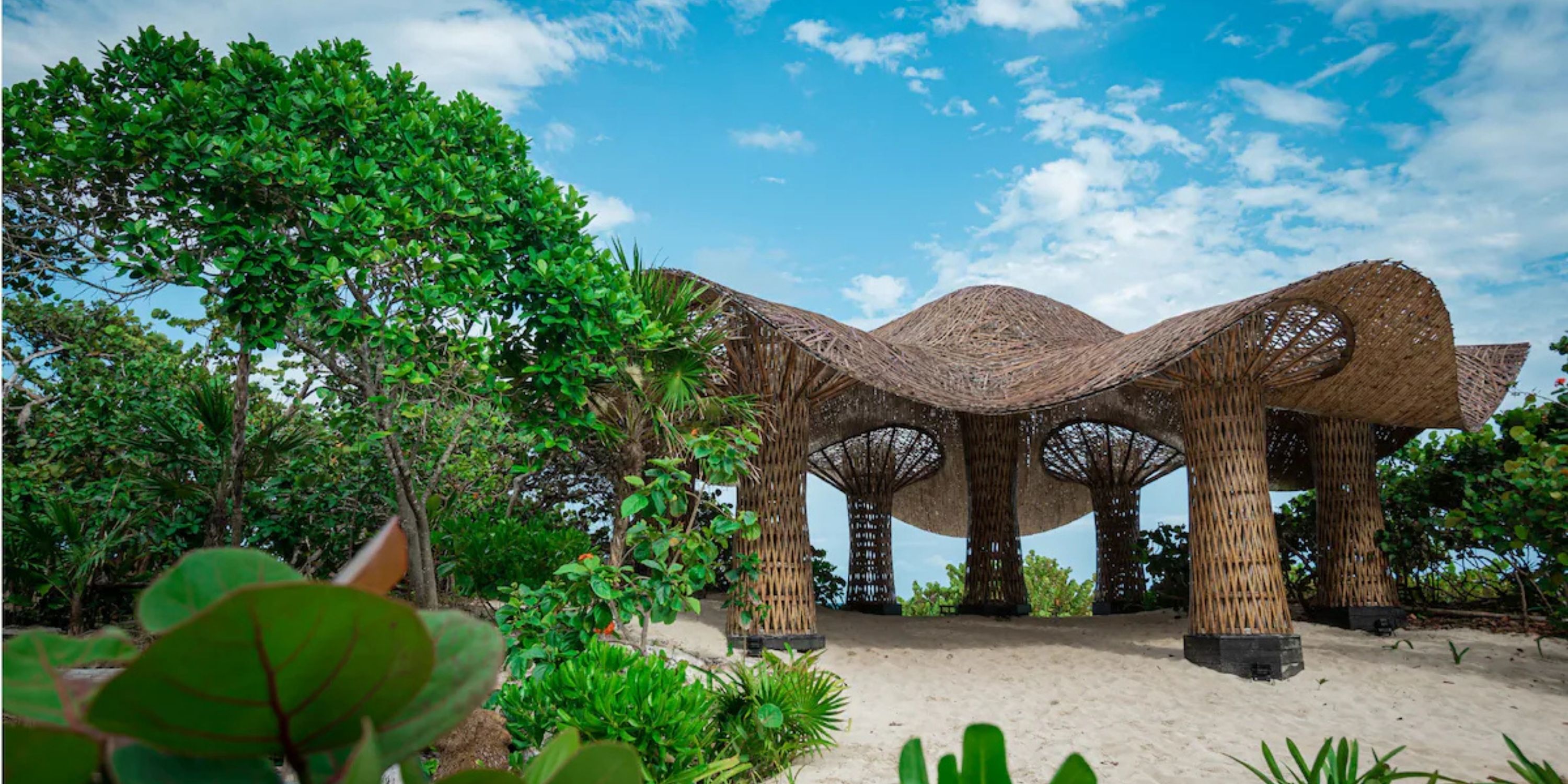 Sandos Playacar pavilion, ideal for a destination wedding, nestled in lush greenery under blue skies.