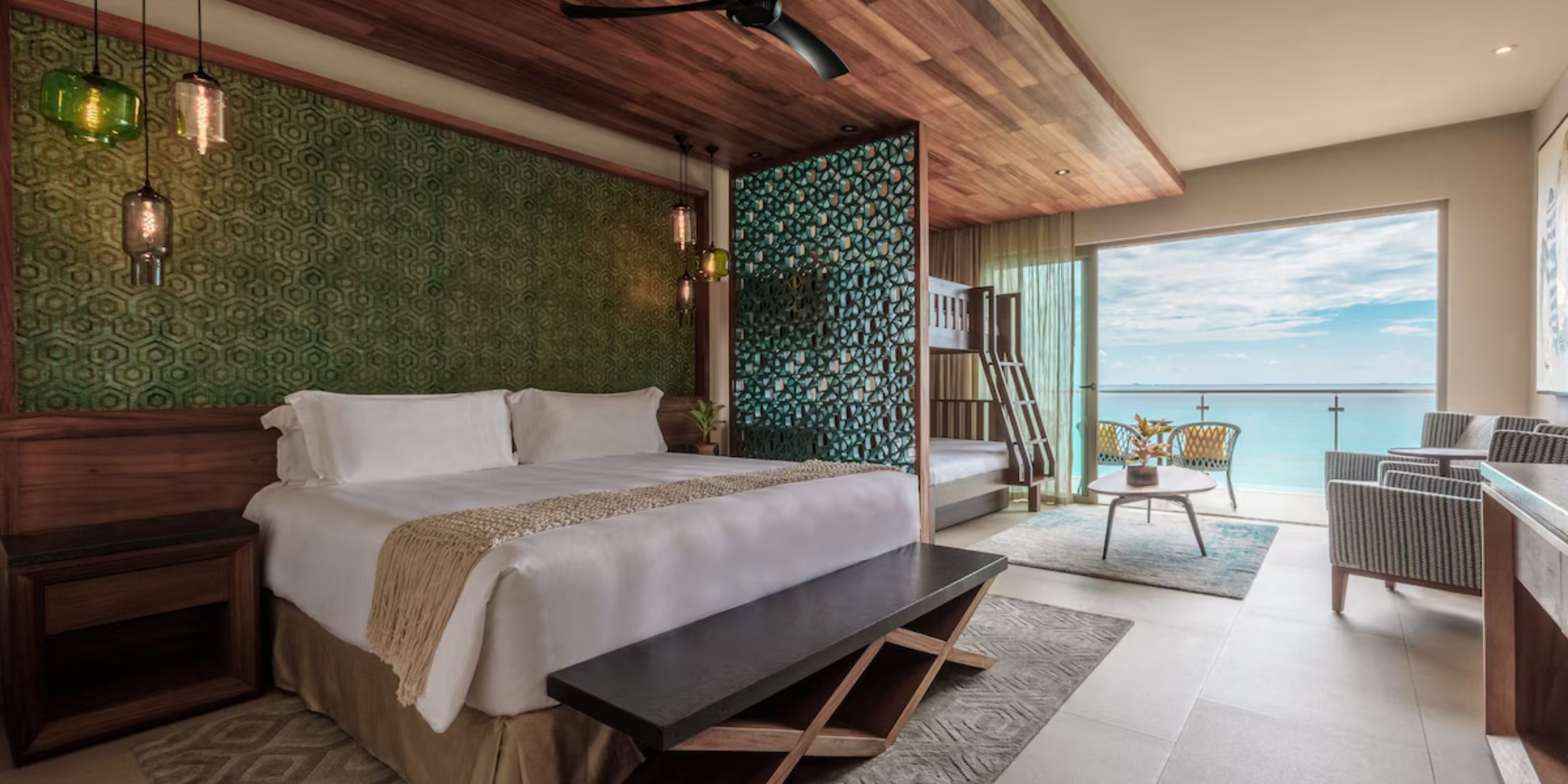 Spacious Sandos Playacar room for a destination wedding: large bed, bunk beds, seating area, ocean view.