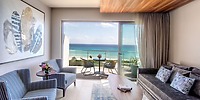 Modern room at Sandos Playacar, ideal for a destination wedding, with ocean view, balcony, sofa, and chairs.