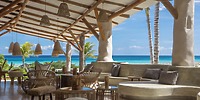 Open-air lounge at Sandos Playacar with wicker furniture and ocean views, perfect for a destination wedding.