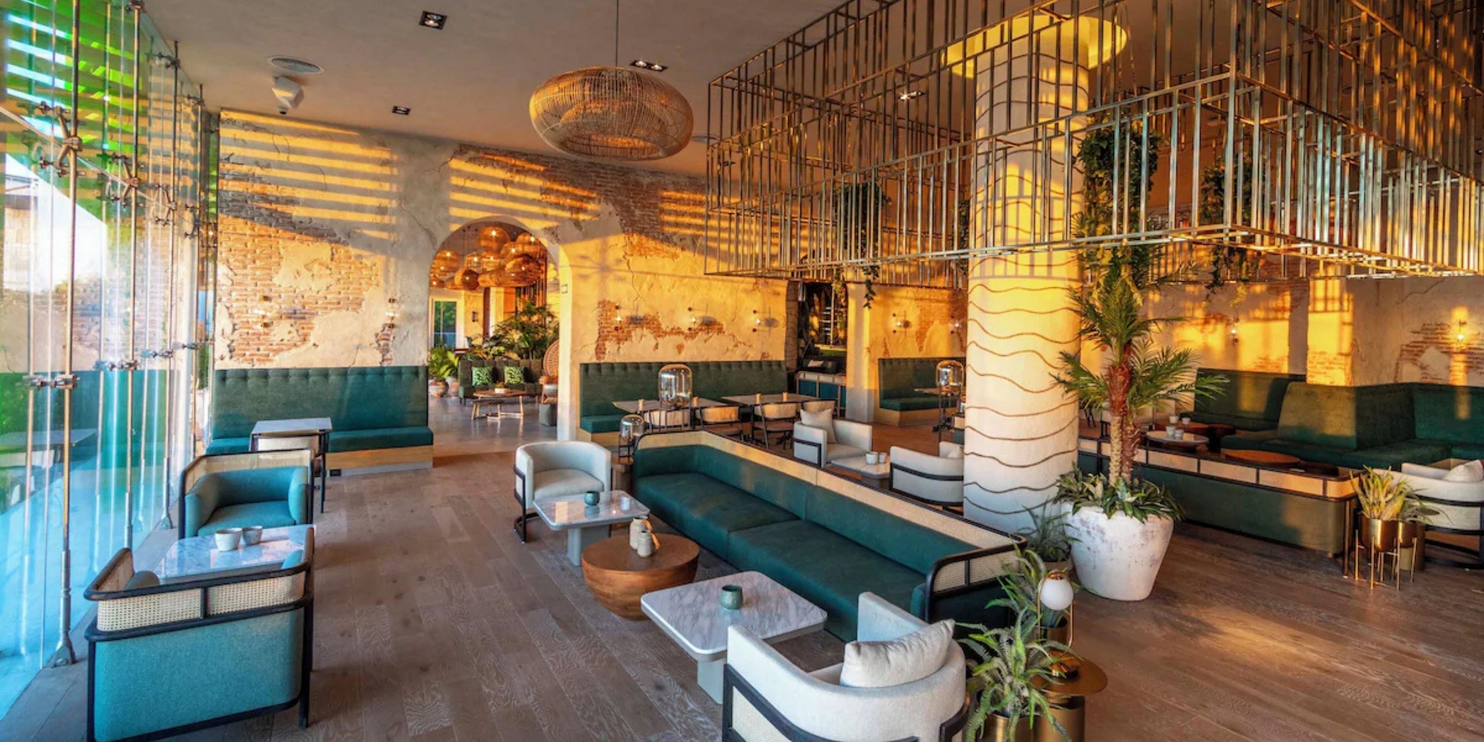 Sandos Playacar lounge, ideal for a destination wedding: green sofas, gold accents, large sunlit windows.