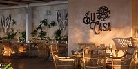 Outdoor seating at Sandos Playacar, ideal for a destination wedding, with wicker chairs and "Su Casa" sign.