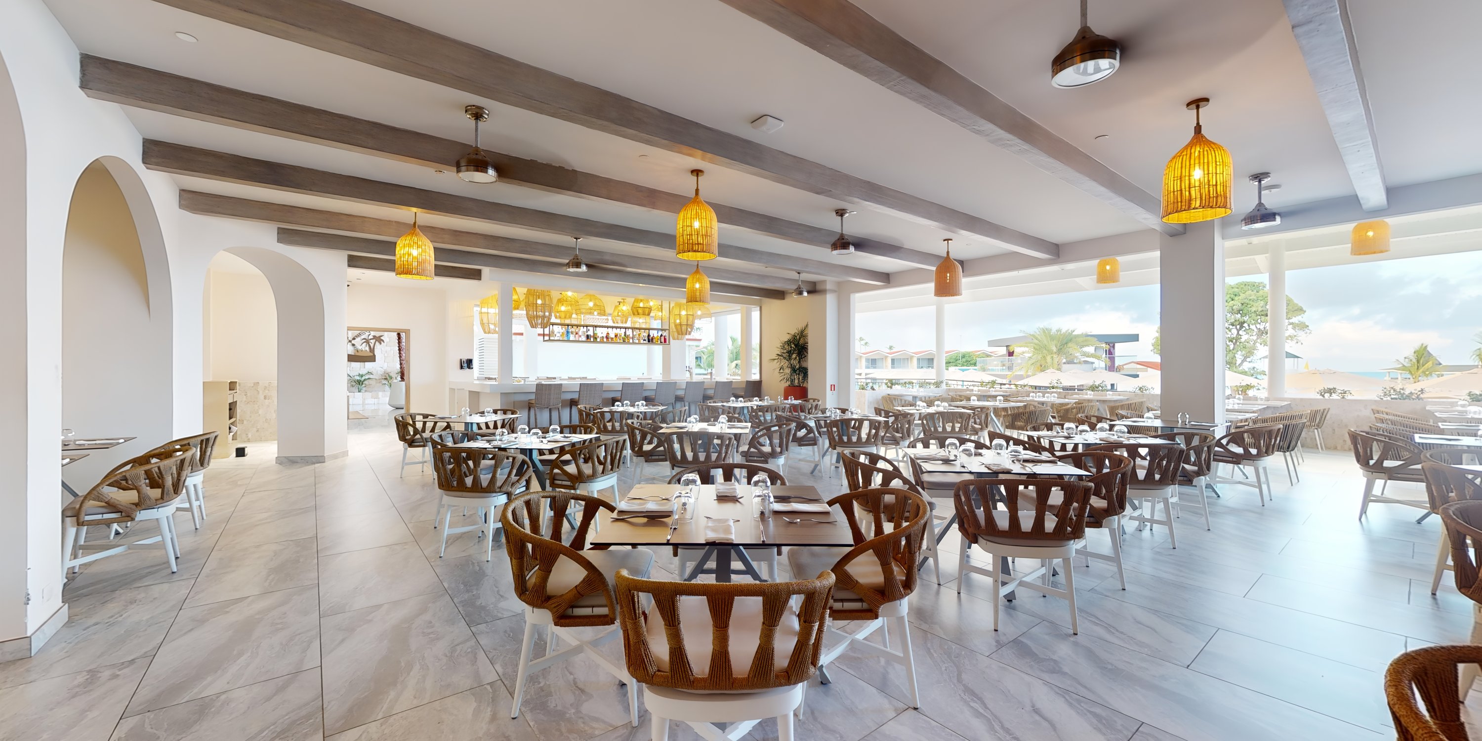 Chic restaurant dining space with wooden tables and pendant lights, set up for a destination wedding event.
