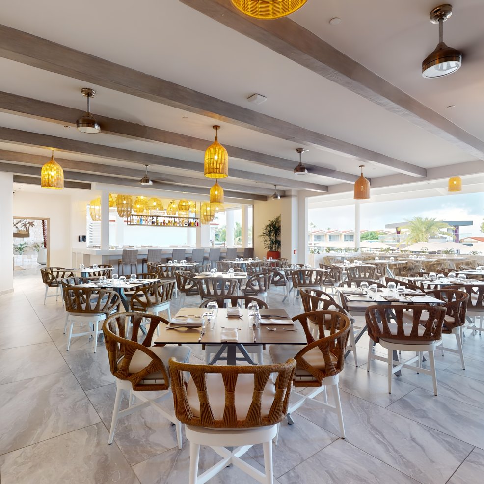 Chic restaurant dining space with wooden chairs, set tables&mdash;ideal for a stylish destination wedding.