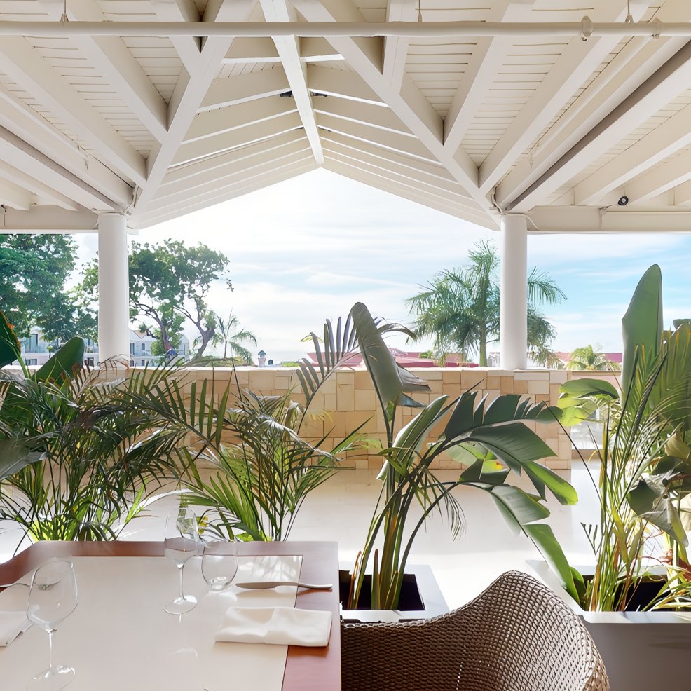 Outdoor dining area with a wedding table set, tropical plants, and scenic views for a destination wedding.