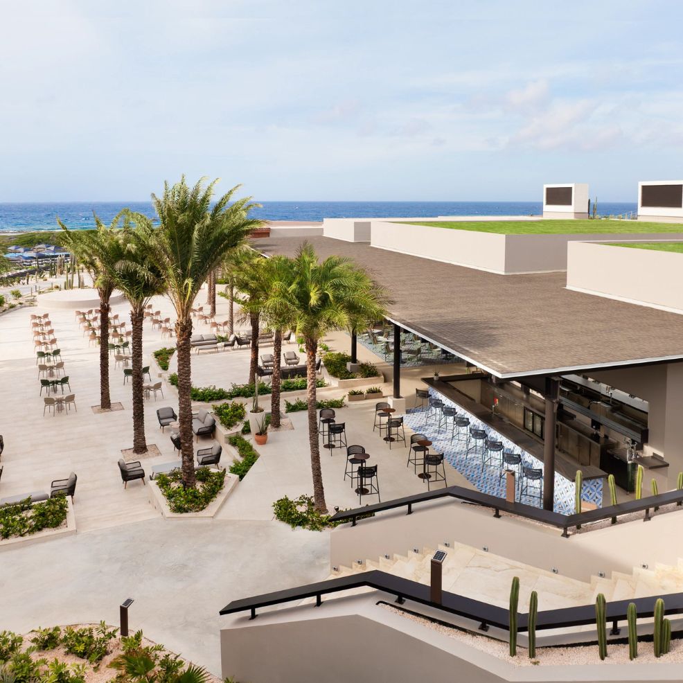 Elegant outdoor bar and seating area with palm trees&mdash;perfect for a destination wedding by the ocean.