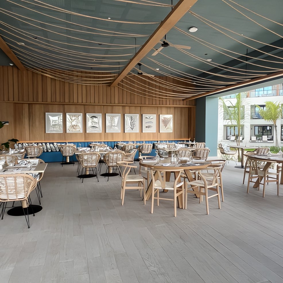 Chic restaurant venue with wooden furniture, tables set for a destination wedding, and framed wall art.