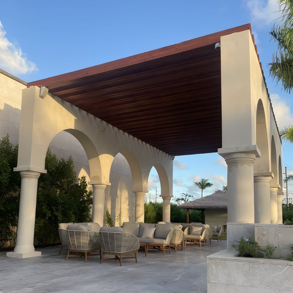 Outdoor lounge area with modern sofas beneath a grand pergola, ideal for a destination wedding setting.