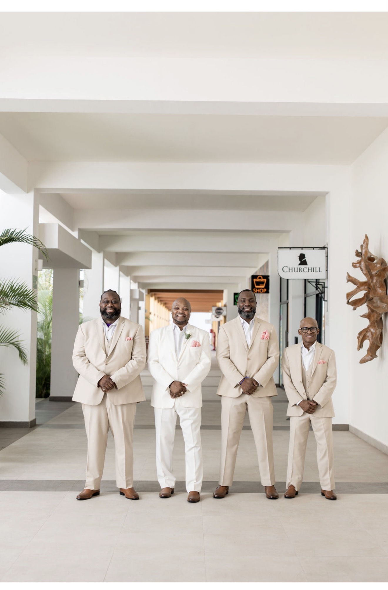 Four men in suits model Catherine and Carlos (Copy), side by side in a corridor at a destination wedding.