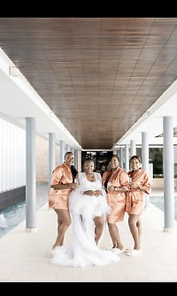 Bride in Catherine and Carlos gown with bridesmaids in satin robes at a destination wedding by the pool.