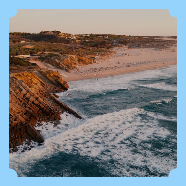 Waves crash on rocky cliffs as the sun sets, creating a breathtaking backdrop for a destination wedding.