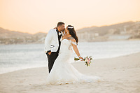 Tiffany and Anthony pose on the beach at sunset, holding wedding flowers at their destination wedding.