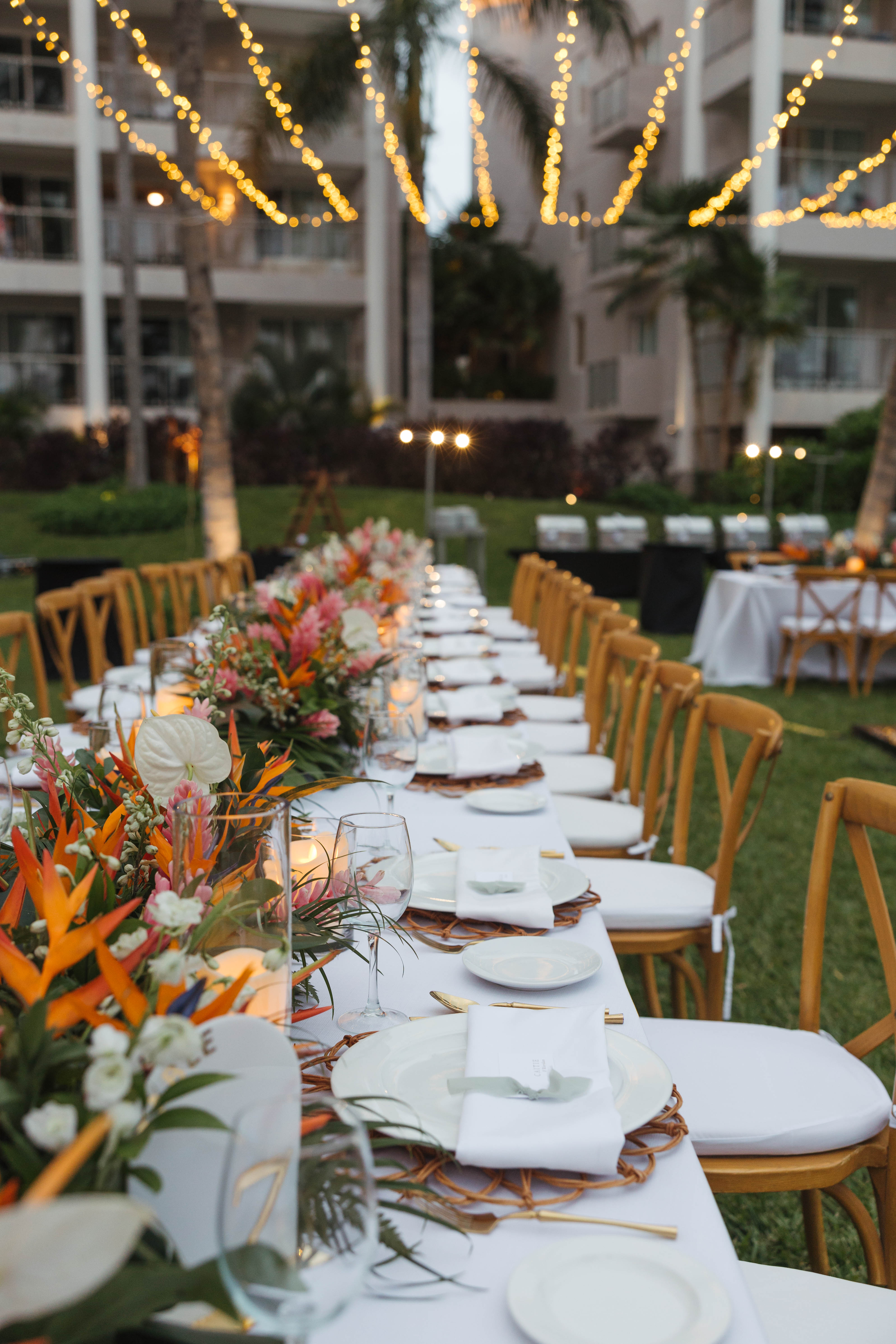 Tiffany and Anthony&rsquo;s destination wedding table with flowers, plates, candles, and string lights.