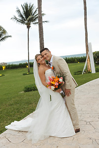 Tiffany and Anthony smile in wedding attire at their destination wedding, palm trees in the background.