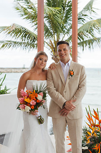 Tiffany and Anthony (Copy) pose outdoors at their destination wedding with tropical flowers and palm trees.