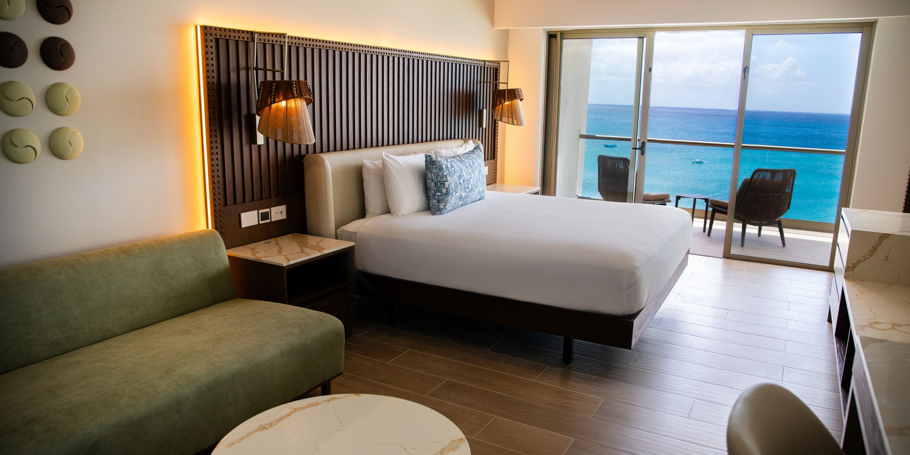 Royalton Vessence Barbados room perfect for a destination wedding, with bed, sofa, balcony, and ocean view.