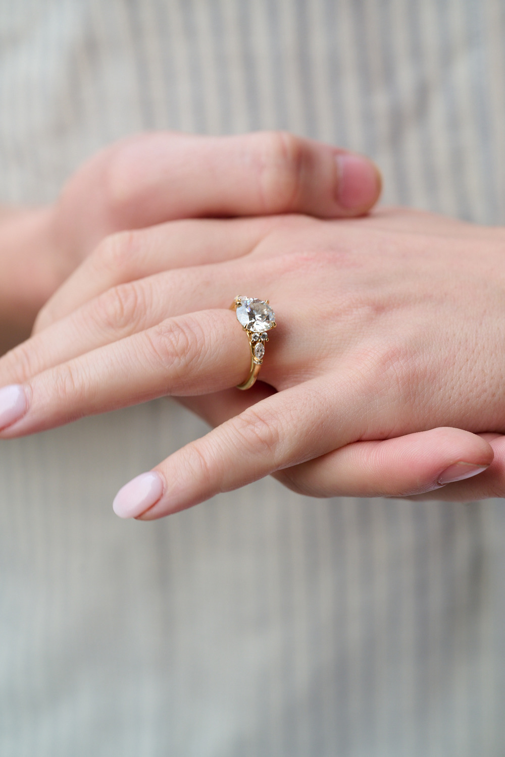 A hand wearing a gold wedding ring with a central diamond and smaller stones, perfect for a destination wedding.