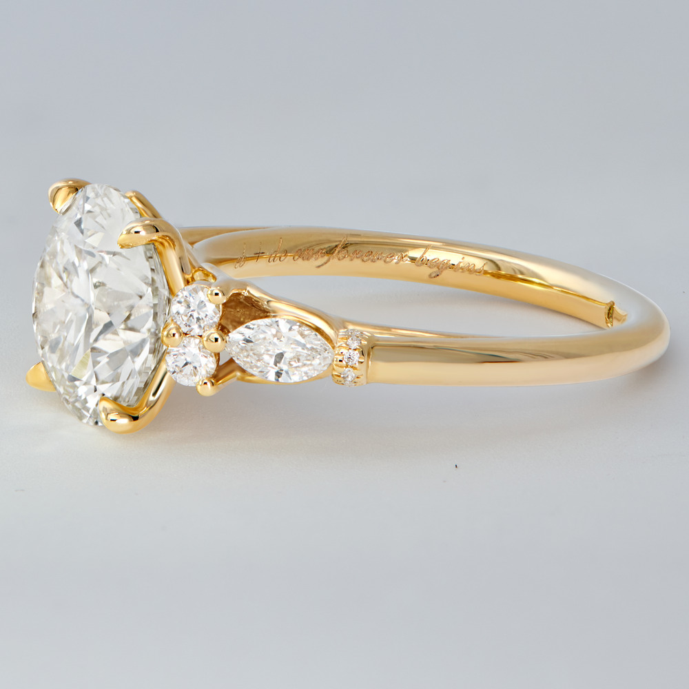Gold wedding ring with a large oval diamond, sparkling side stones, and an engraved band for a destination wedding.