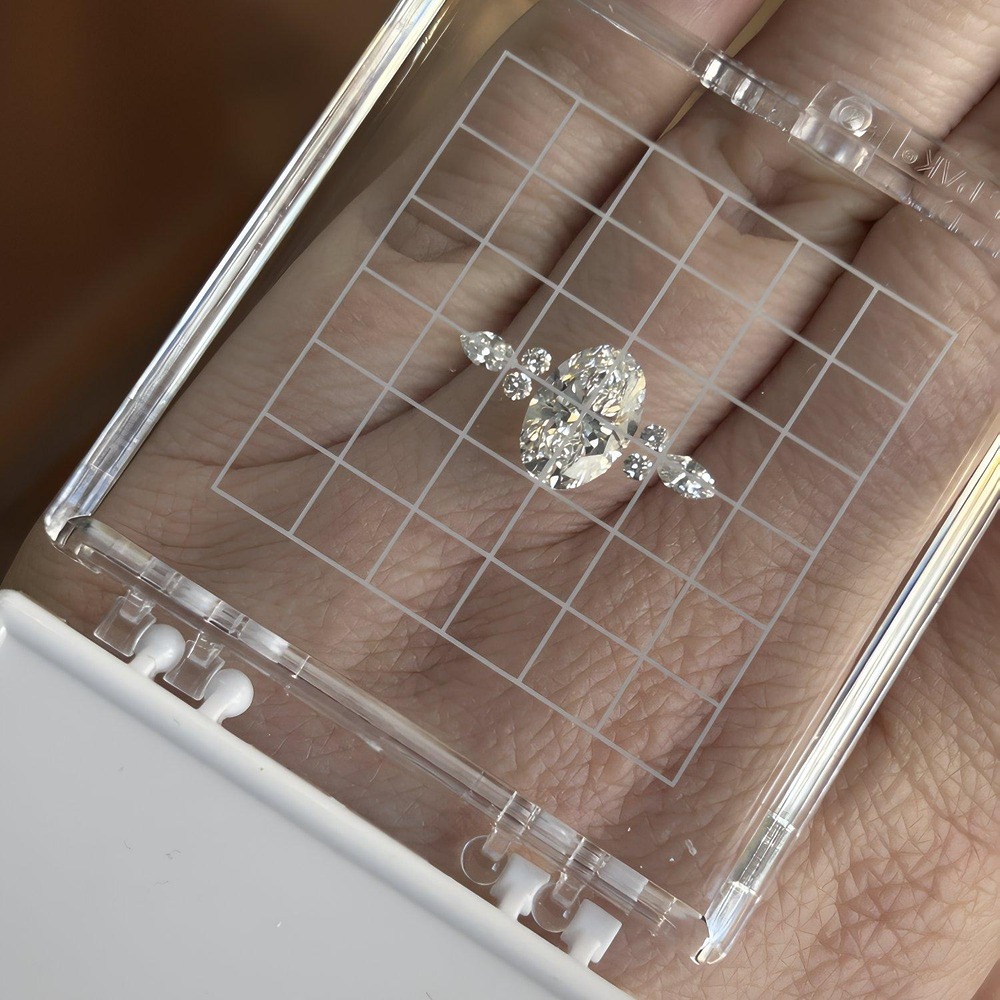 A wedding diamond ring with side stones showcased in a clear, grid-patterned display case.
