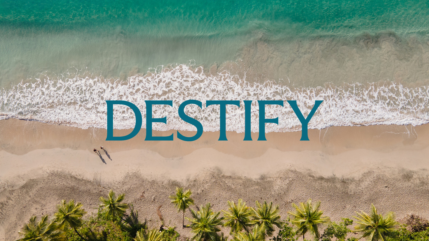Aerial view of a tropical destination wedding beach with "DESTIFY" written on the sand.