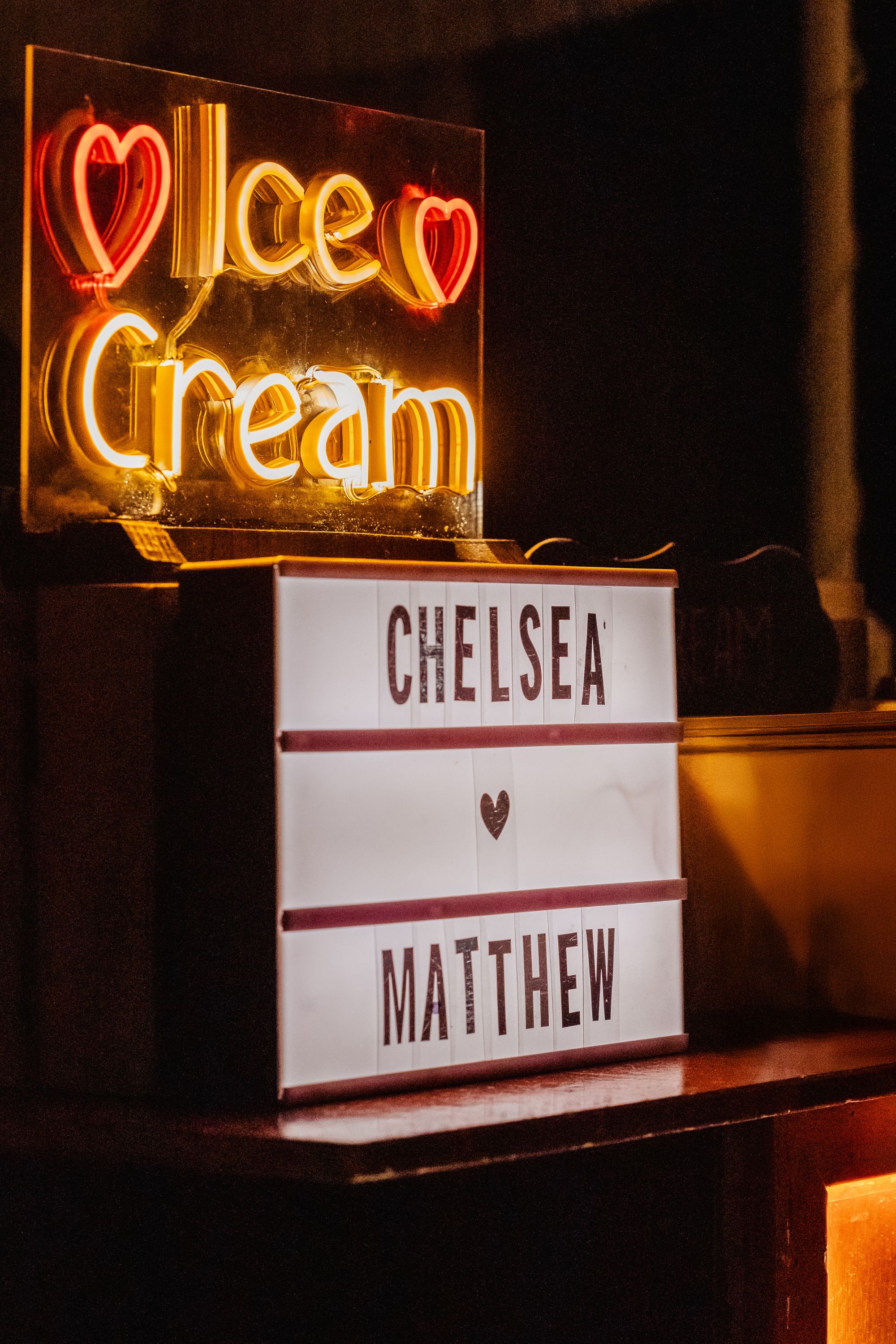 Neon "Ice Cream" sign above a lightbox reading "Kathryn and Mike" at a destination wedding.