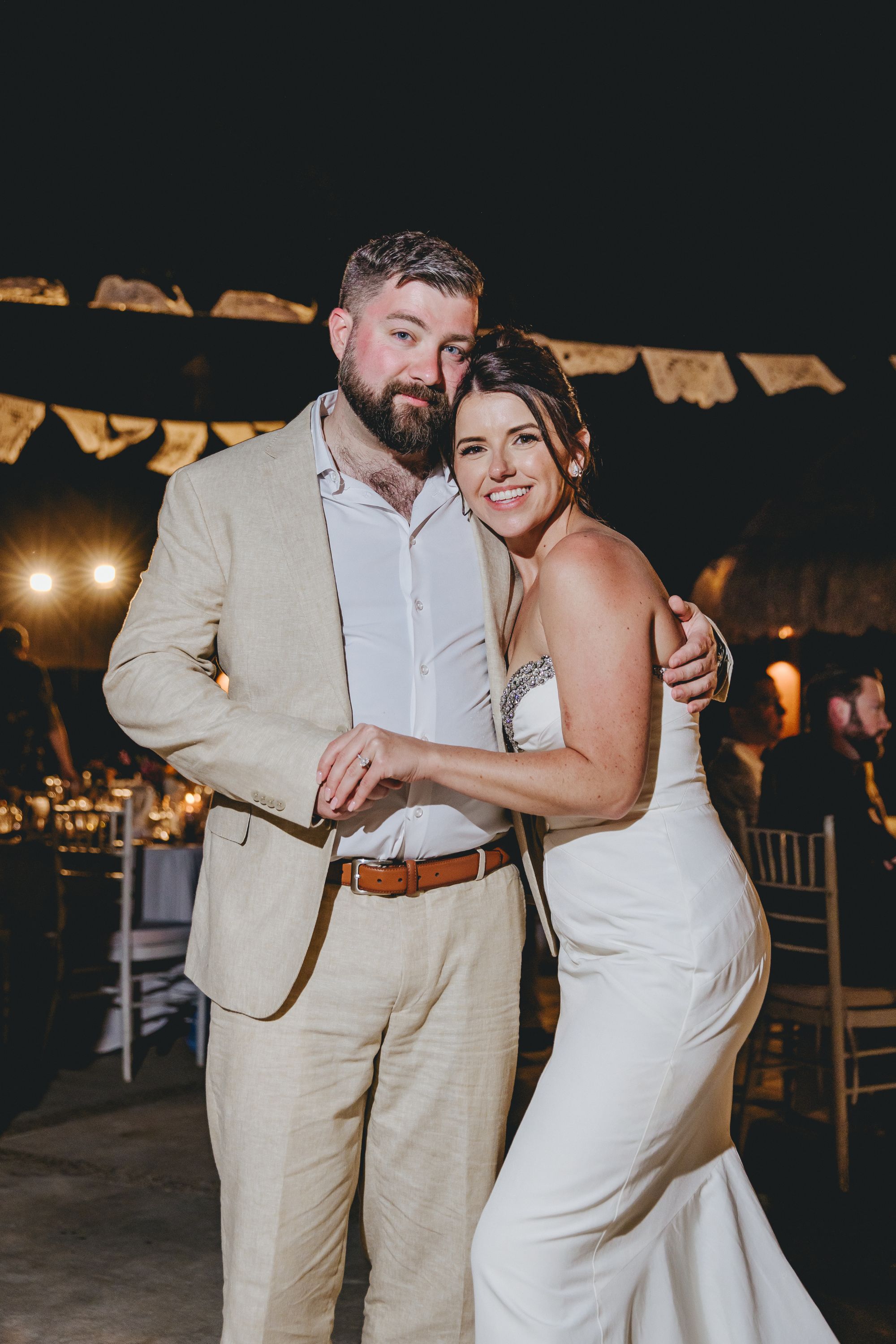 Kathryn and Mike (Copy) smile in wedding attire at a nighttime outdoor destination wedding celebration.