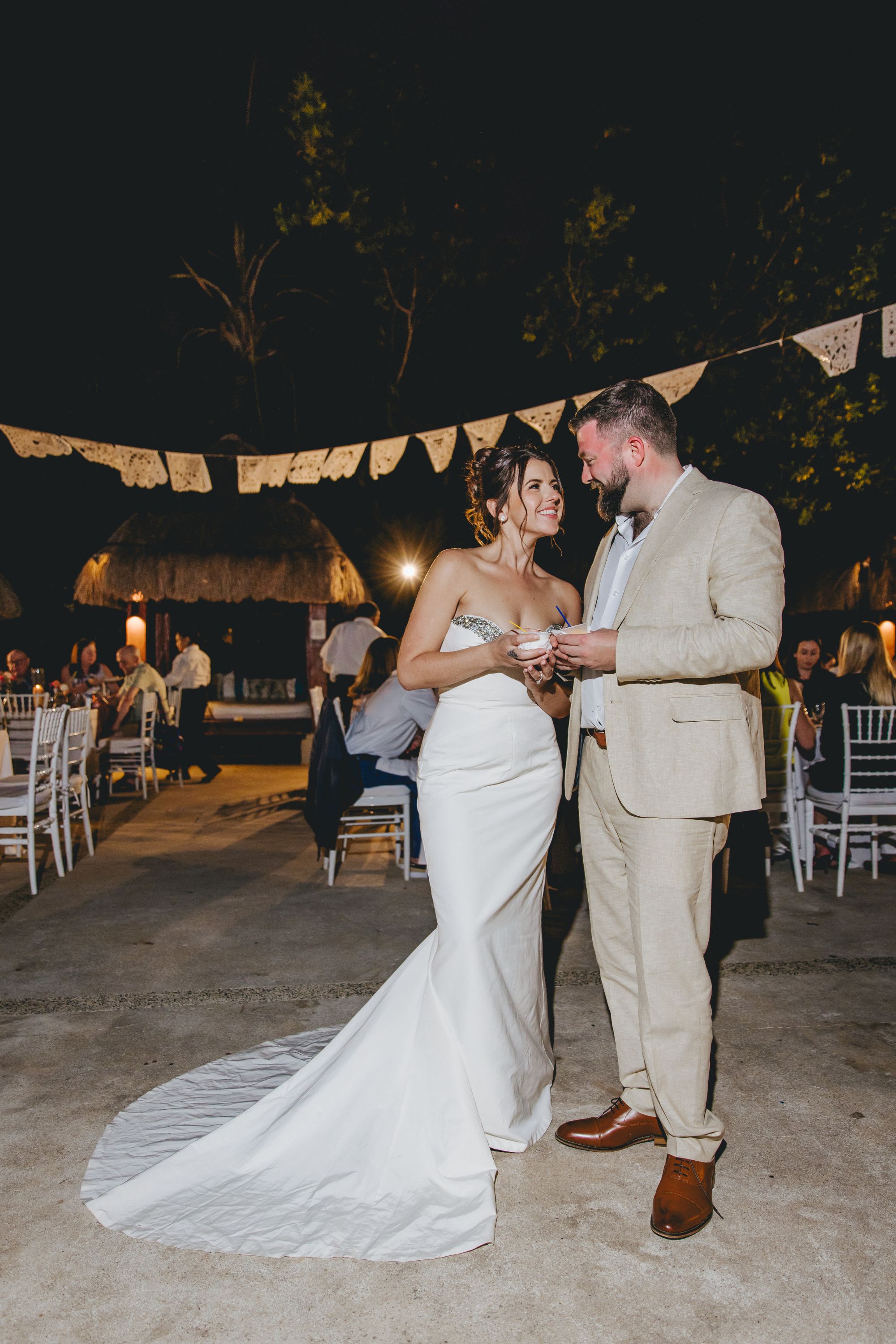 Kathryn and Mike hold hands and smile at each other outdoors at night during their destination wedding.
