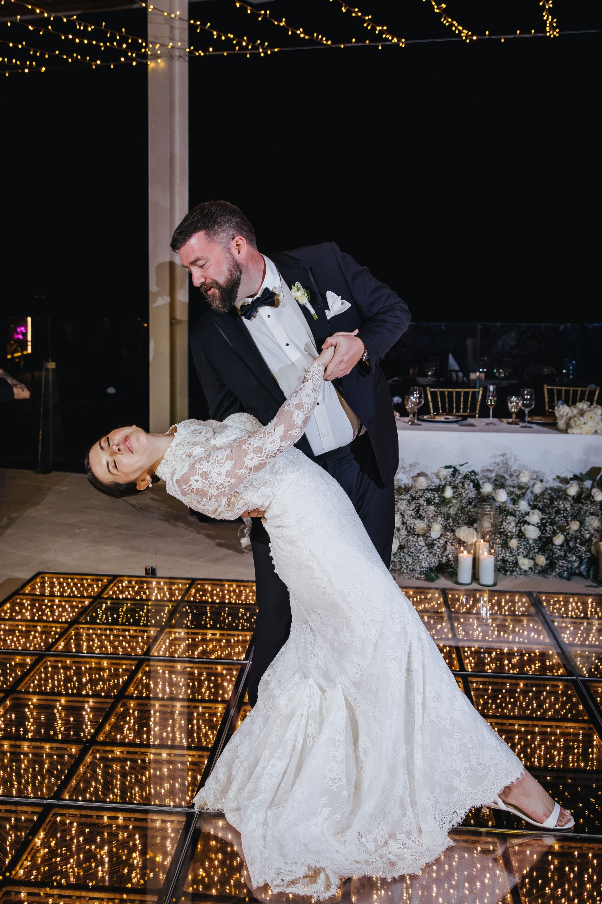 Kathryn and Mike dance at their destination wedding on a glowing floor beneath string lights.
