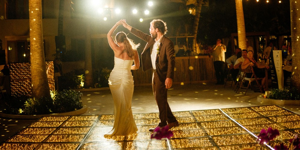 Ethan and Erica share a dance on a glowing outdoor floor at their destination wedding at night.