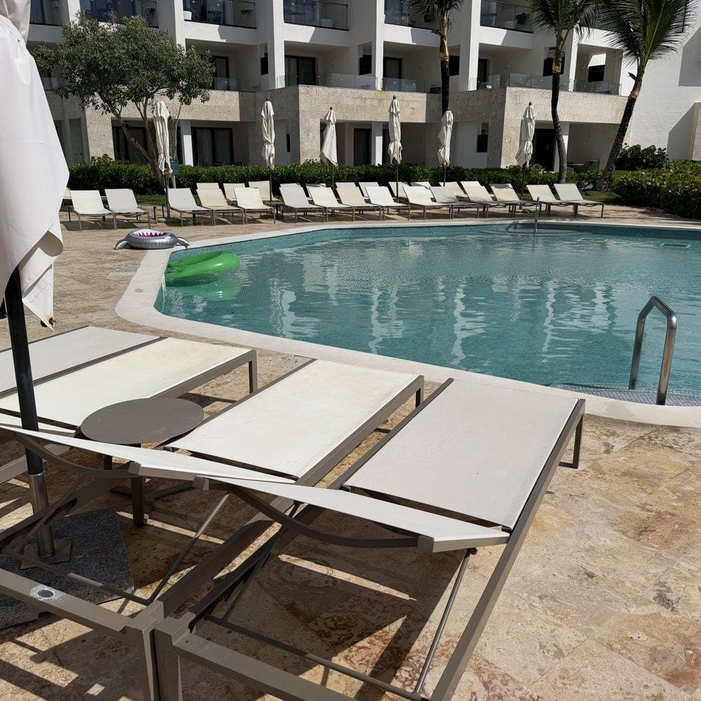 Empty lounge chairs beside a hotel pool, perfect for a destination wedding, with floats in the water.
