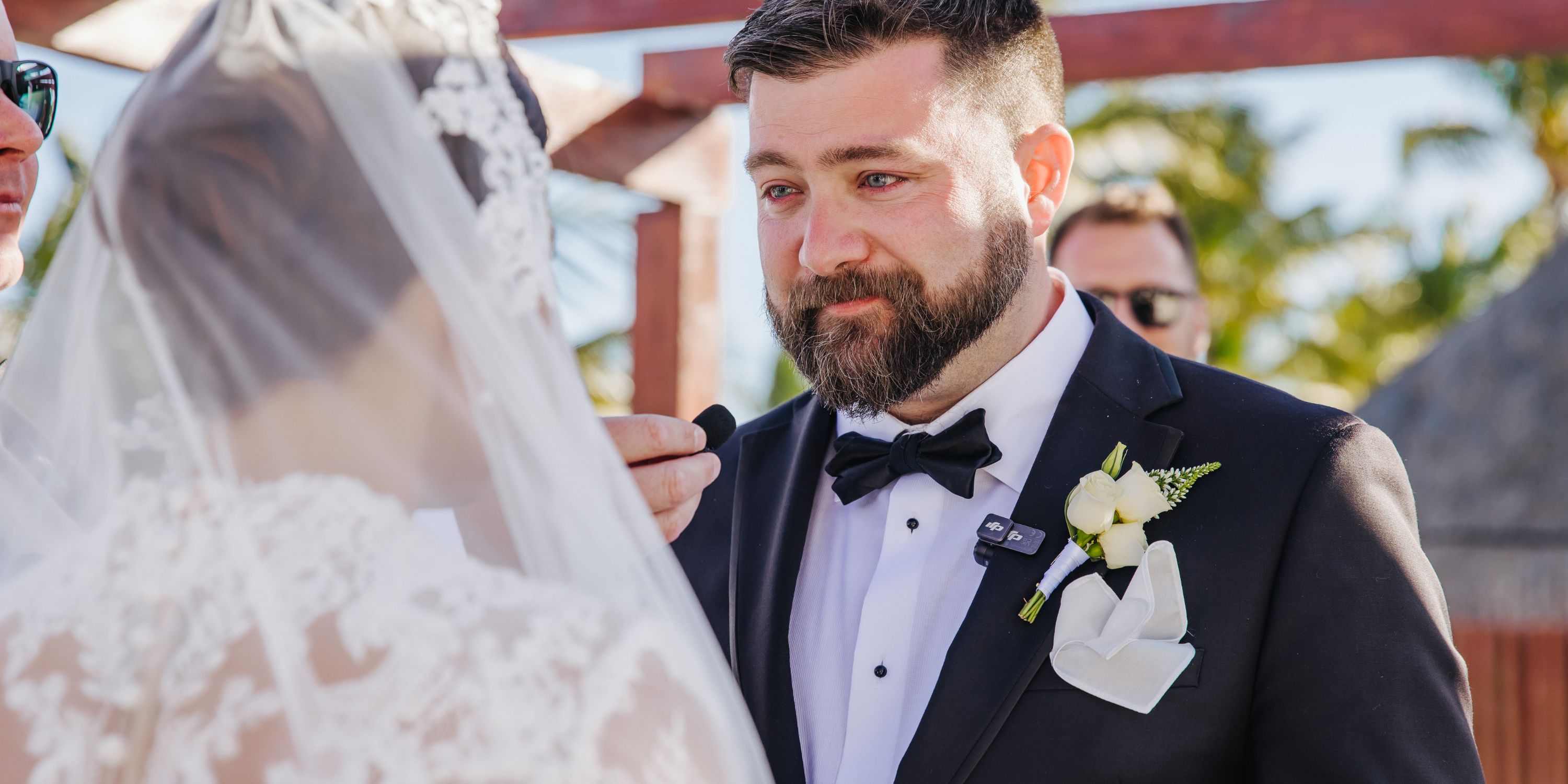 An emotional groom in a black tuxedo at Kathryn and Mike's beautiful destination wedding ceremony.