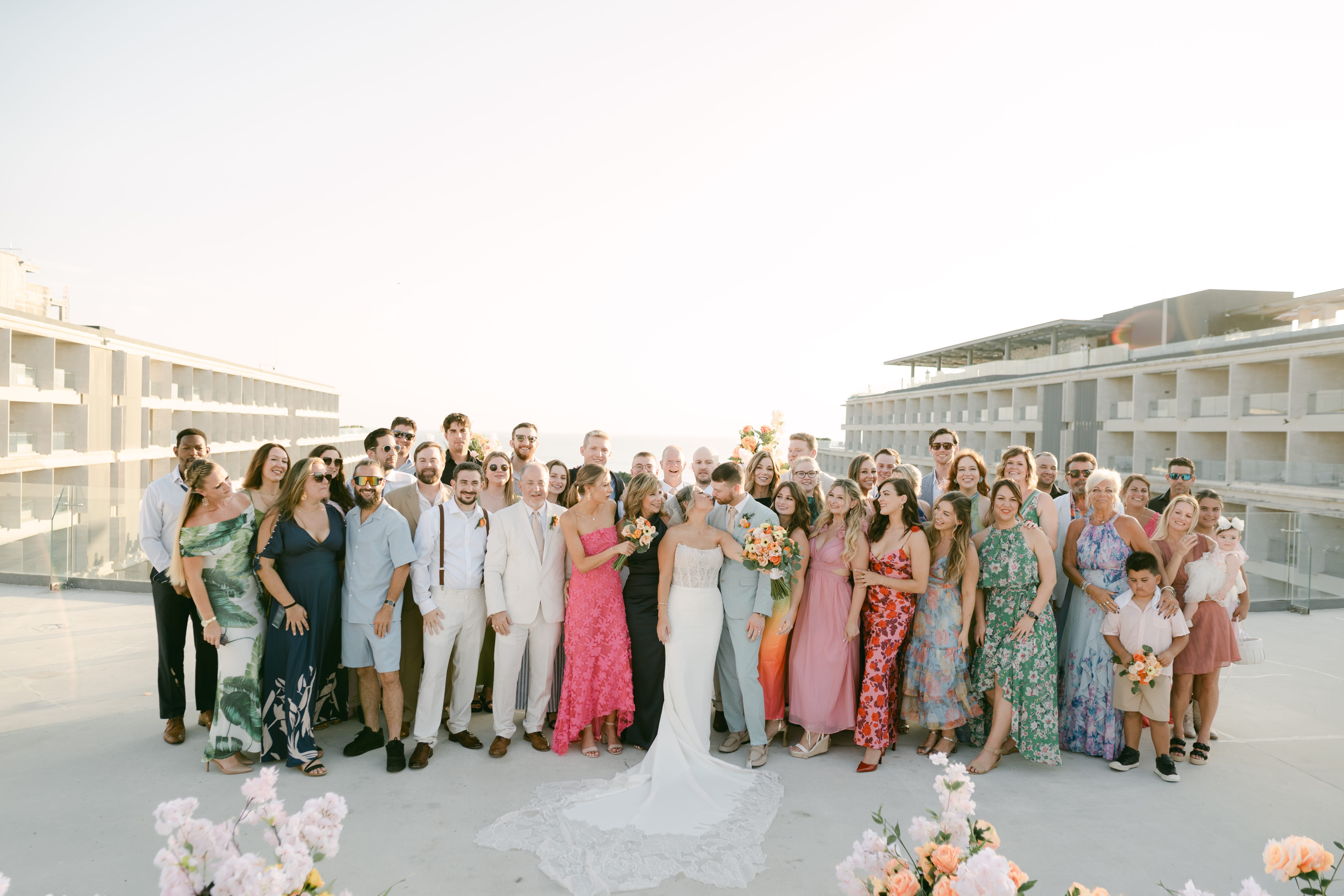 Lauren and Ben's destination wedding group poses outdoors with modern buildings in the background.