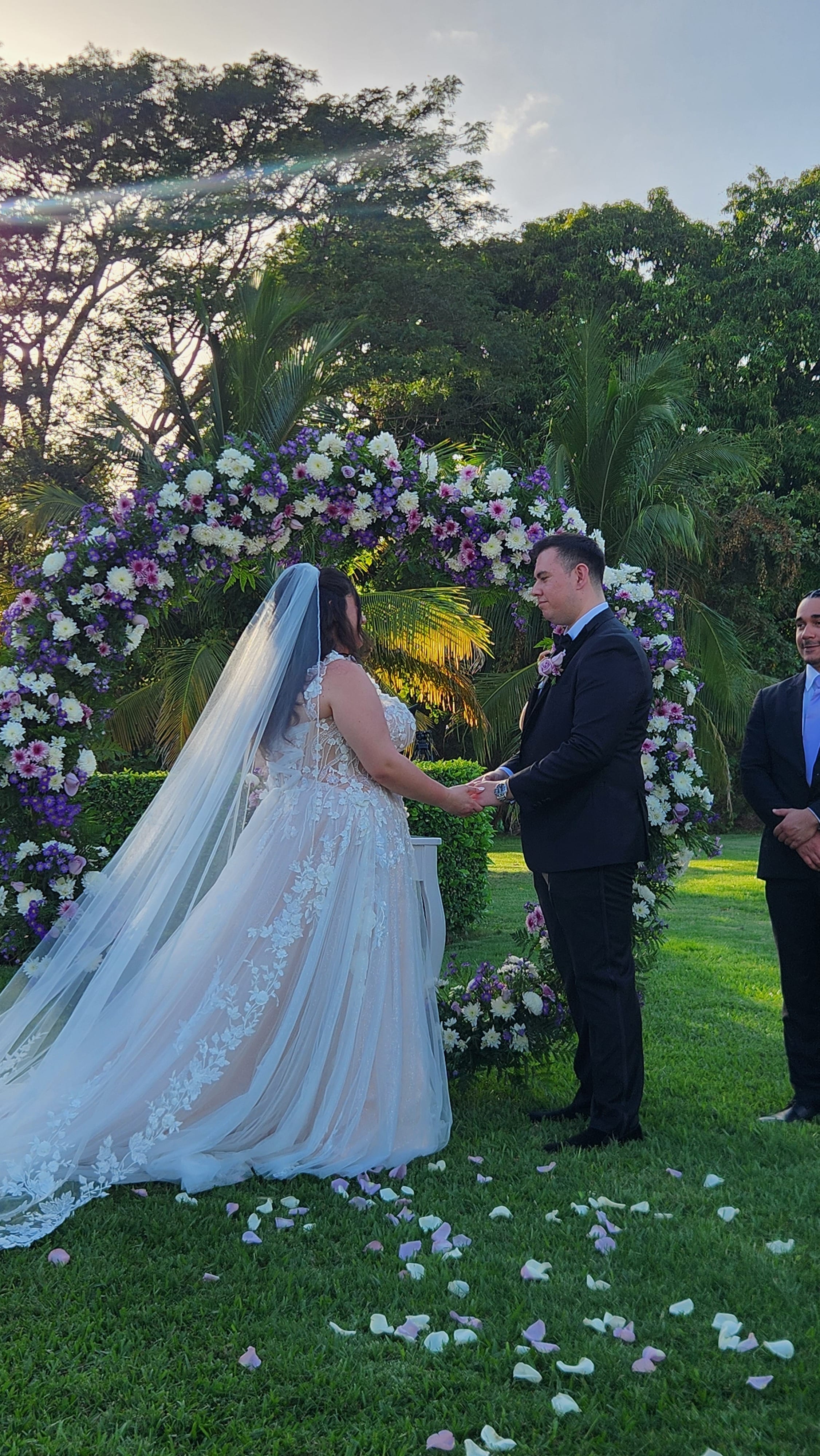 Ashley and Zach exchange vows beneath a floral arch at their picturesque outdoor destination wedding.