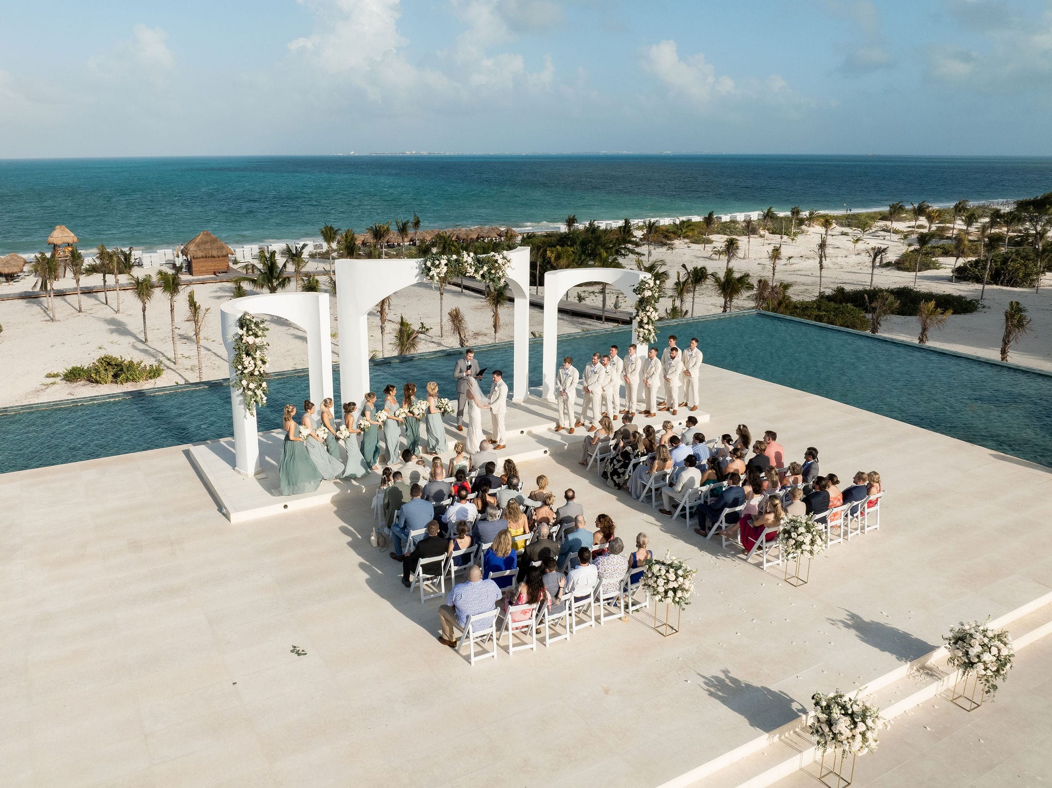 Lauren and Ben's destination wedding by the ocean, guests seated with bridal party and officiant nearby.