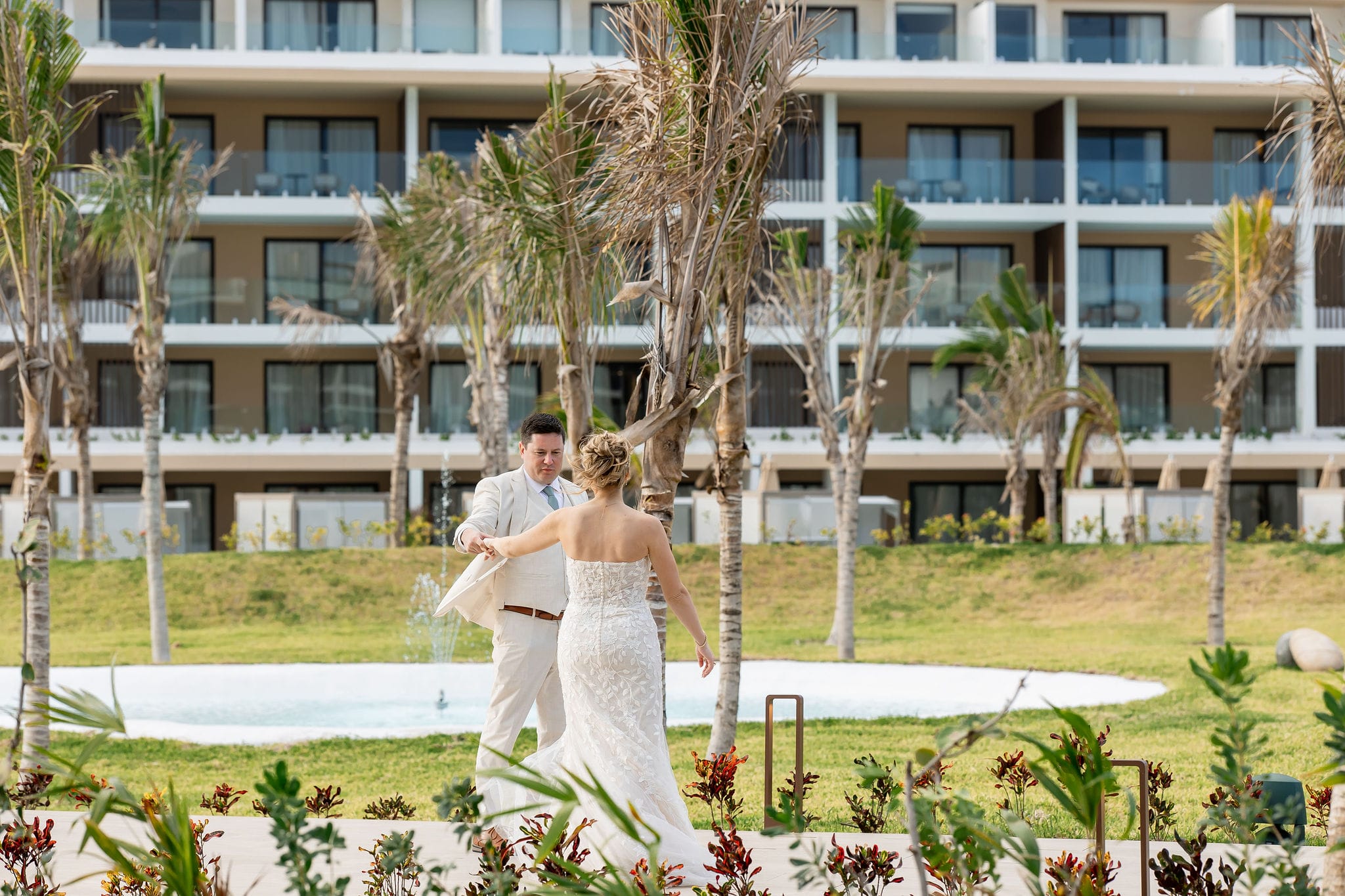 Lauren and Ben share a dance outside by palm trees at a modern hotel during their destination wedding.
