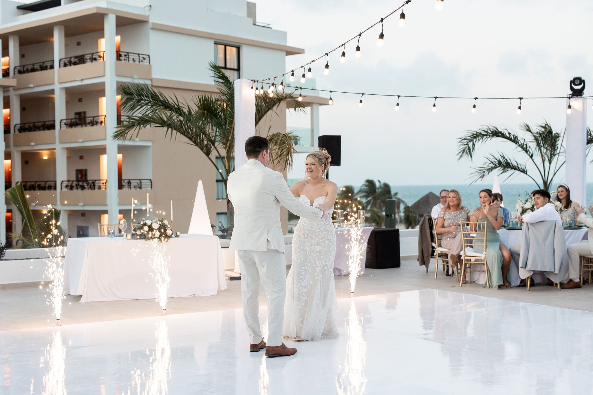 Lauren and Ben share their first dance at a destination wedding, guests and lights creating a magical scene.