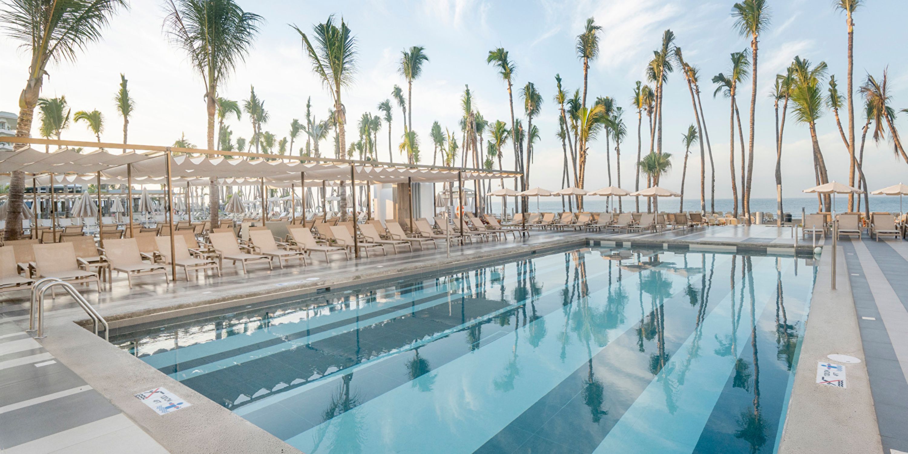 Hotel Riu Jalisco: outdoor pool with lounge chairs, palm trees, ocean views&mdash;ideal for weddings.